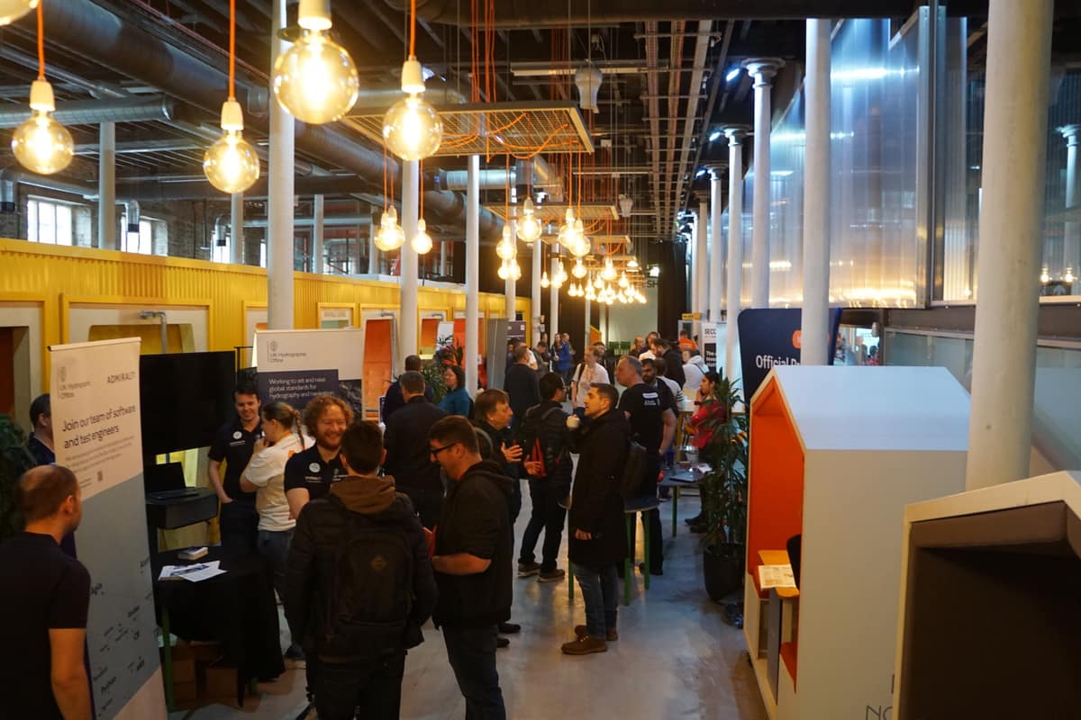 Attendees chatting around sponsor stands in the exhibition area.