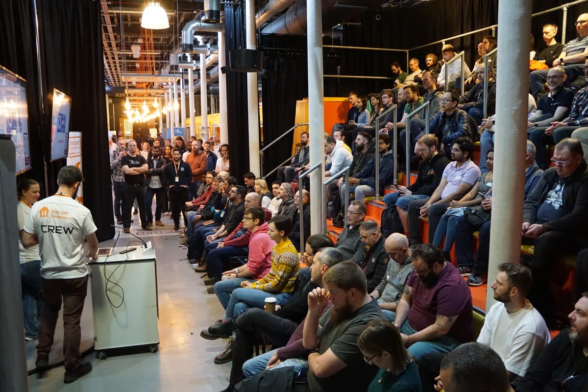A crew member introducing a session to a packed room.