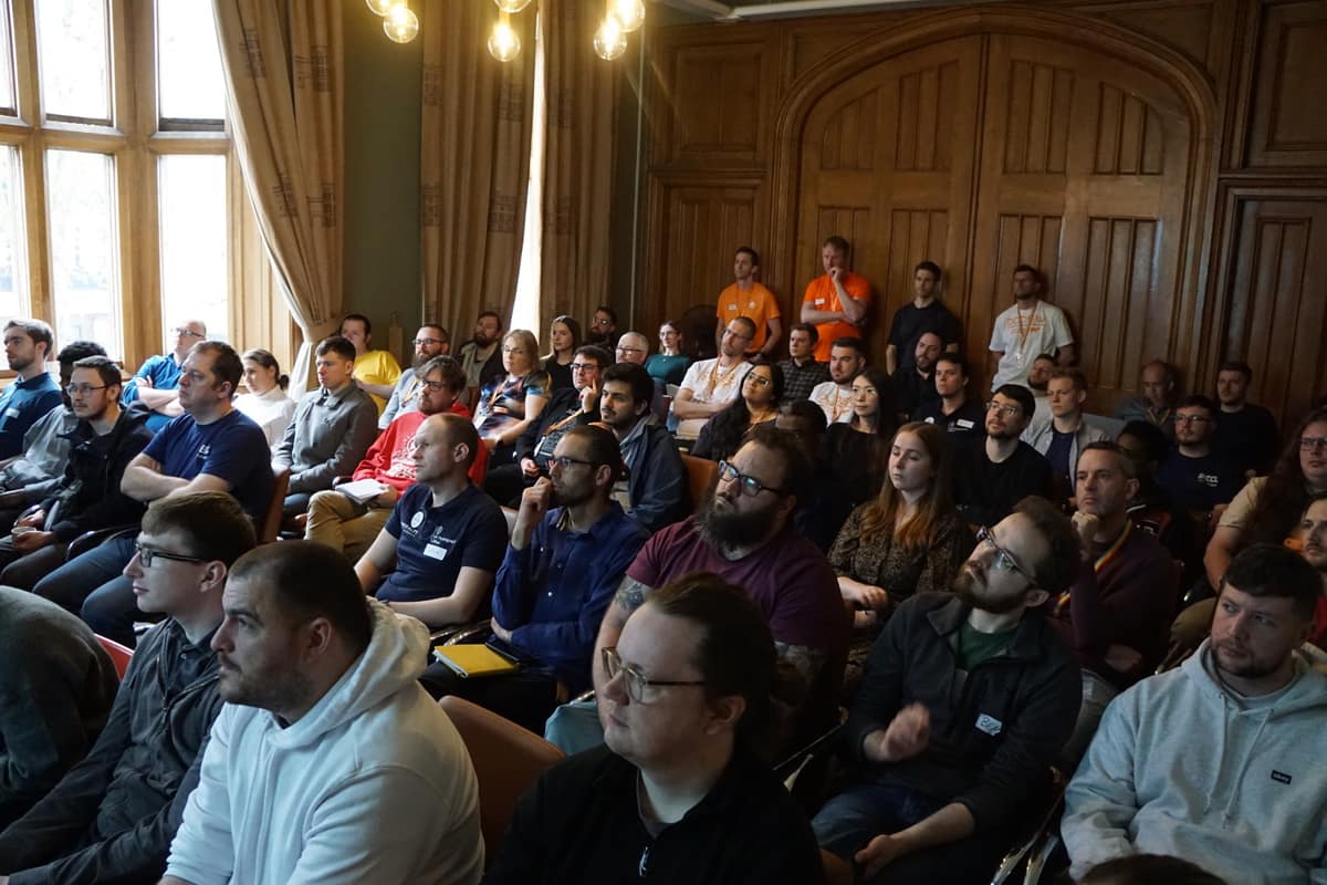 Attendees listening to a session in a wood-panelled room.